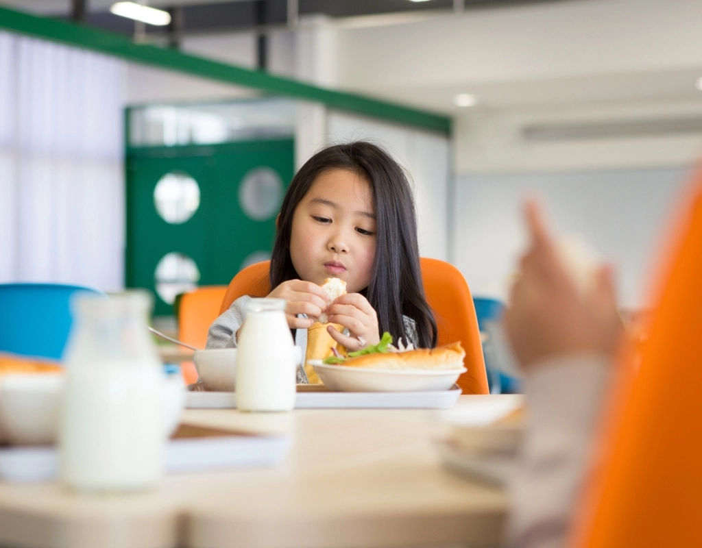 un enfant qui mange à la cantine